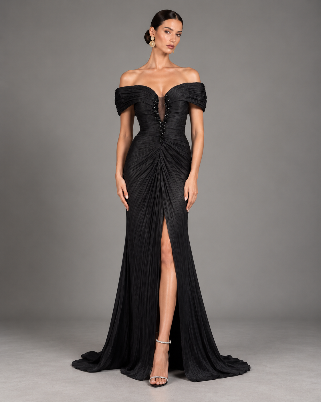 Black floor-length evening gown with an off-the-shoulder sculpted neckline, a finely pleated bodice, and a beaded illusion center-front plunge.